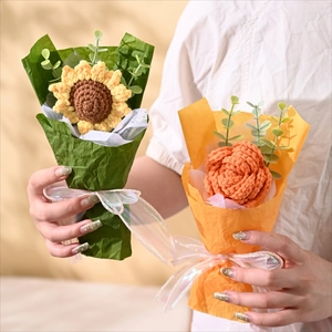 Close-up of model holding handmade knitted sunflower and rose bouquets with silk ribbons