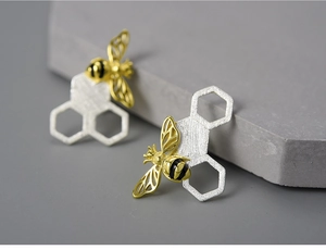 Macro view of handmade S925 silver honeycomb stud earrings with a golden bee detail