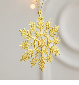 Close-up of golden glitter snowflake ornament with hanging string for Christmas trees