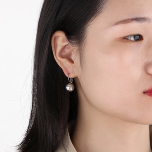 Minimalist silver stainless steel ball earrings worn by a model on a white background