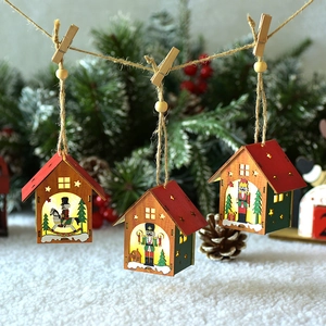 Lighted wooden Christmas house ornaments with nutcracker and hanging rope on pine branch