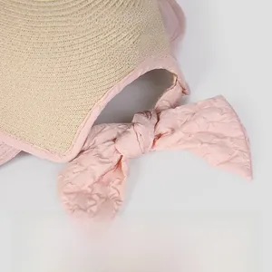 Close-up of pink seersucker bow and woven straw detail on foldable women's sun hat