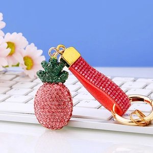 Portachiavi ananas rosa con strass e cinturino di cristallo su una tastiera bianca