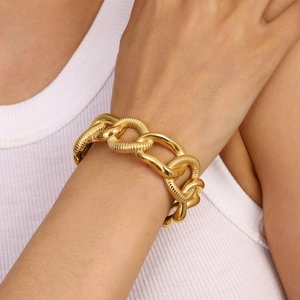 Detail of chunky gold chain bracelet with mixed smooth and textured links on model