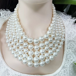 Detailed view of layered white imitation pearl necklace on a white lace dress