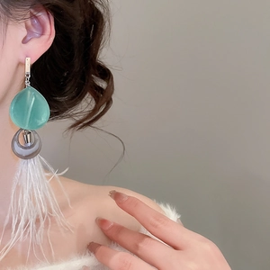 Détail de boucles d'oreilles ethniques avec perles de résine vert menthe et plumes