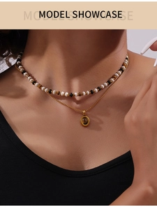 Close-up of double-layer necklace with beaded chain and tiger eye stone pendant on a model