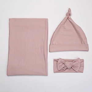Detail shot of dusty pink newborn swaddle set with matching hat and bow headband