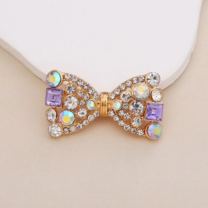 Detailed view of a gold-plated bow charm with purple crystals and sparkling rhinestones