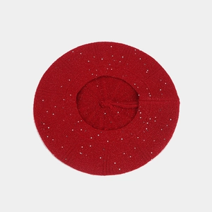 Detailed top view of a red knit beret featuring sparkling silver sequins and top stem