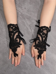Detailed close-up of vintage black lace fingerless gloves with floral embroidery and satin ribbons