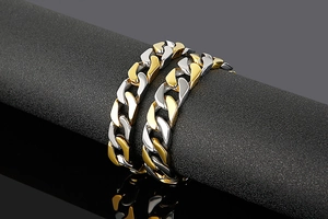 Polished two-tone gold and silver Cuban link bracelets on a professional black display stand