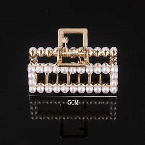 Close-up of a 5cm golden alloy hair claw with elegant pearls and crystal rhinestones