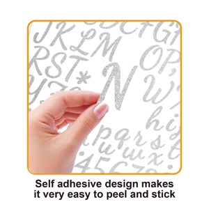 Close-up showing a hand peeling a silver glitter self-adhesive letter N from the backing