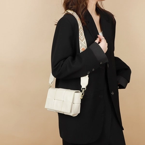 White woven leather crossbody bag with geometric fabric strap shown on shoulder