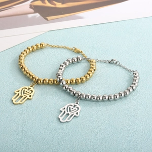 Gold and silver beaded Hamsa hand bracelets on light blue textured background