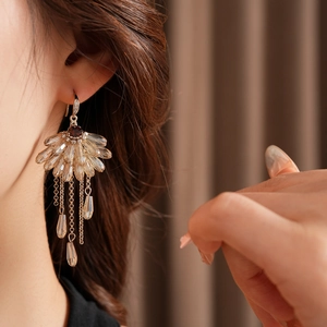 Detail of bohemian fan-shaped champagne crystal drop earrings on elegant model