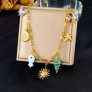 Detail van gouden ketting met kleurrijke keramische zeeschelpen en hangers van tropische vissen