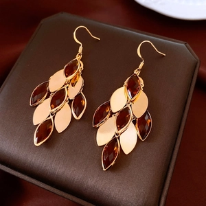 Detail of 18K gold-plated earrings featuring amber crystal leaves on dark textured box