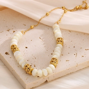 Detailed macro view of gold-plated titanium steel chain with elegant white beads and spacers