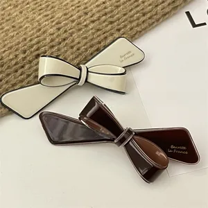 Detail view of French retro resin bow hair clips in cream white and coffee brown colors