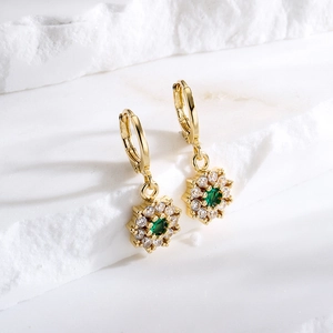18K gold plated snowflake earrings with emerald green zircon stone on marble