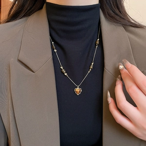 Close-up of vintage heart-shaped tiger eye pendant necklace on gold chain with beads