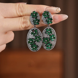 Detail of vintage oval drop earrings featuring green zircon flowers in black nickel finish