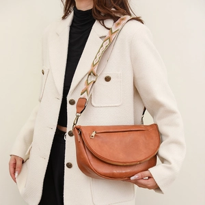 Close-up of vintage brown leather crescent chest bag with colorful ethnic woven strap