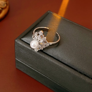 Detailed view of silver open ring with zircons and pearls on a jewelry box