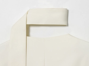 Dettaglio del blazer bianco con scollo a V che mostra la trama del tessuto e le cuciture pulite