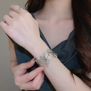Dettaglio ravvicinato di bracciale rigido floreale vintage e anello aperto con texture