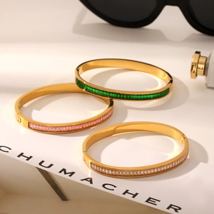 Detailed view of gold stainless steel bangles set with green pink and white zircons
