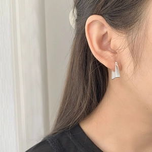 Macro shot of minimalist geometric S925 sterling silver earrings worn by a model
