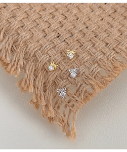 Detail view of gold and silver bow zircon earrings on textured linen background
