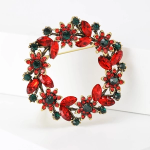 Detailed macro shot of vintage gold wreath brooch with ruby red and emerald green crystals