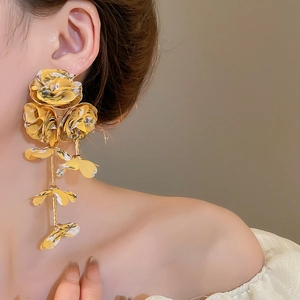 Detail view of yellow chiffon flower tassel earrings worn by a model for vacation style