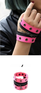Detailansicht eines pinken Punk-Lederarmbands mit Metallösen und schwarzem Reißverschluss