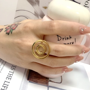 Close-up of golden double-band titanium steel ring worn by model holding pink cup