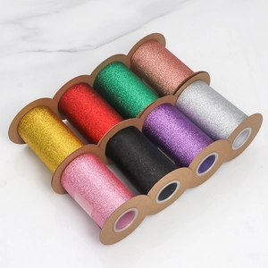 Detail of multi-colored glitter tulle ribbon rolls on marble surface for gift wrapping