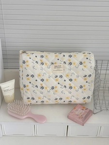 Detail of floral corduroy makeup bag with metal zipper and quilted fabric texture