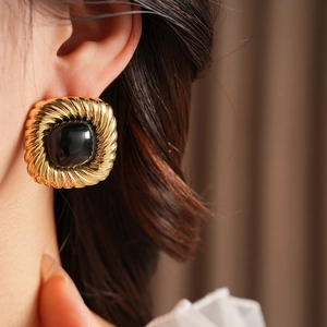 Nahaufnahme von Vintage-Viereck-Ohrringen in Gold mit schwarzem Edelstein am Ohr