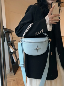Close-up of light blue pebble leather crescent chest bag with silver star logo and chain
