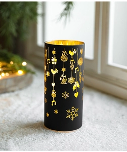 Close-up of black and gold Christmas candle holder with snowflake and bell patterns