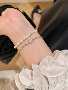 Detail view of pearl and star zircon bracelet set worn against elegant lace and leather