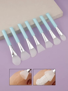 Set of 7 blue silicone face mask brushes with silver metal ferrules on a stone display