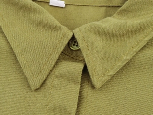 Close-up of green linen shirt neckline showing fabric texture and single button detail