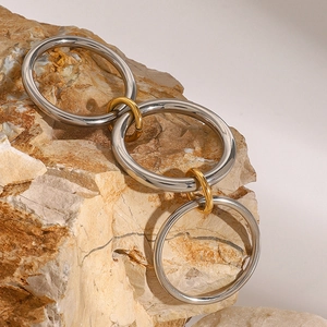 Minimalist interlinked stainless steel rings in silver and gold on a textured stone base