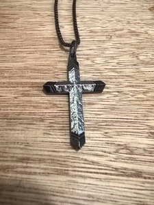 Vue détaillée du pendentif croix noir et argent de style punk sur une chaîne sombre