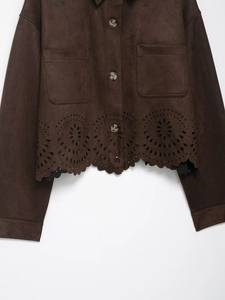 Détail de la veste en daim marron avec ourlet floral découpé au laser et bouton rond